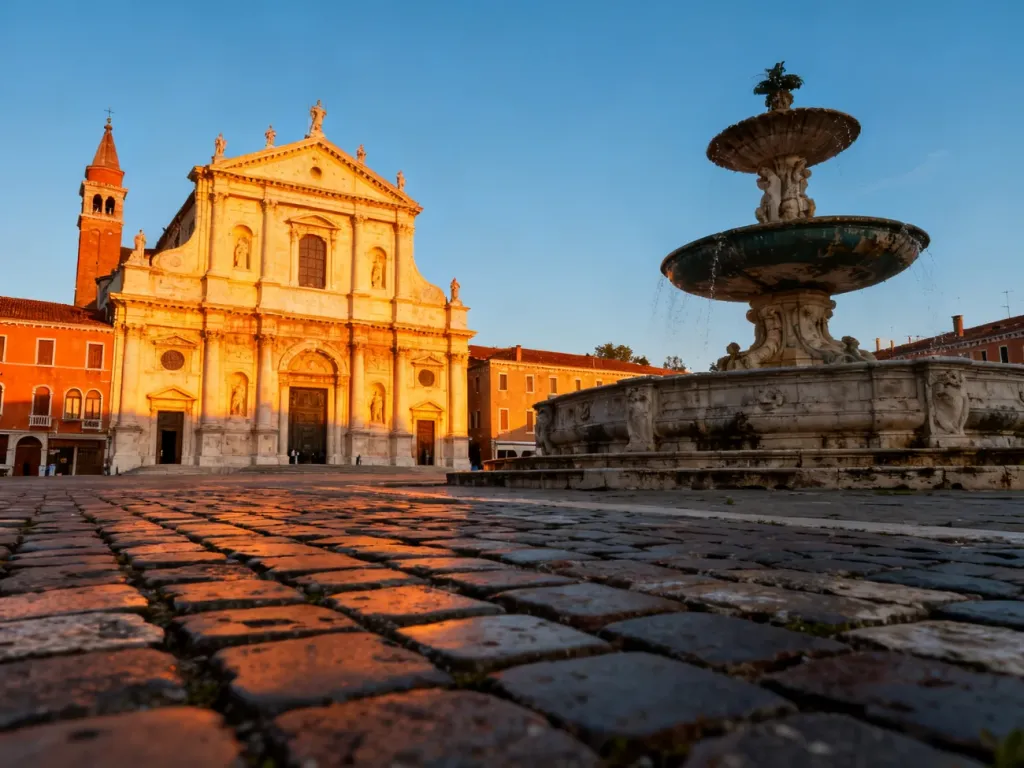 Historyczne centrum Bergamo, Città Alta, z fontanną Contarini i bazyliką Santa Maria Maggiore w blasku zachodzącego słońca.